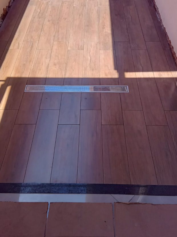 Corredor com porcelanato amadeirado assentado e ralo linear instalado