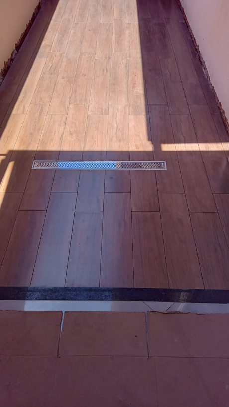 Corredor com piso em porcelanato amadeirado e ralo linear de inox
